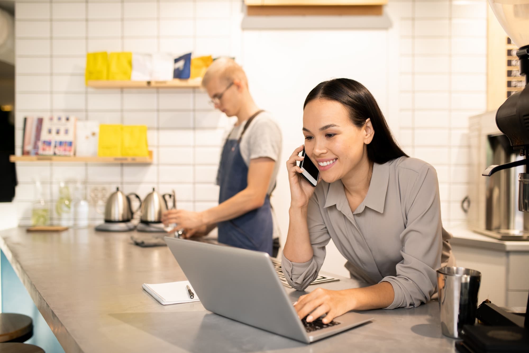 Young manager of restaurant consulting clients on the phone in front of laptop