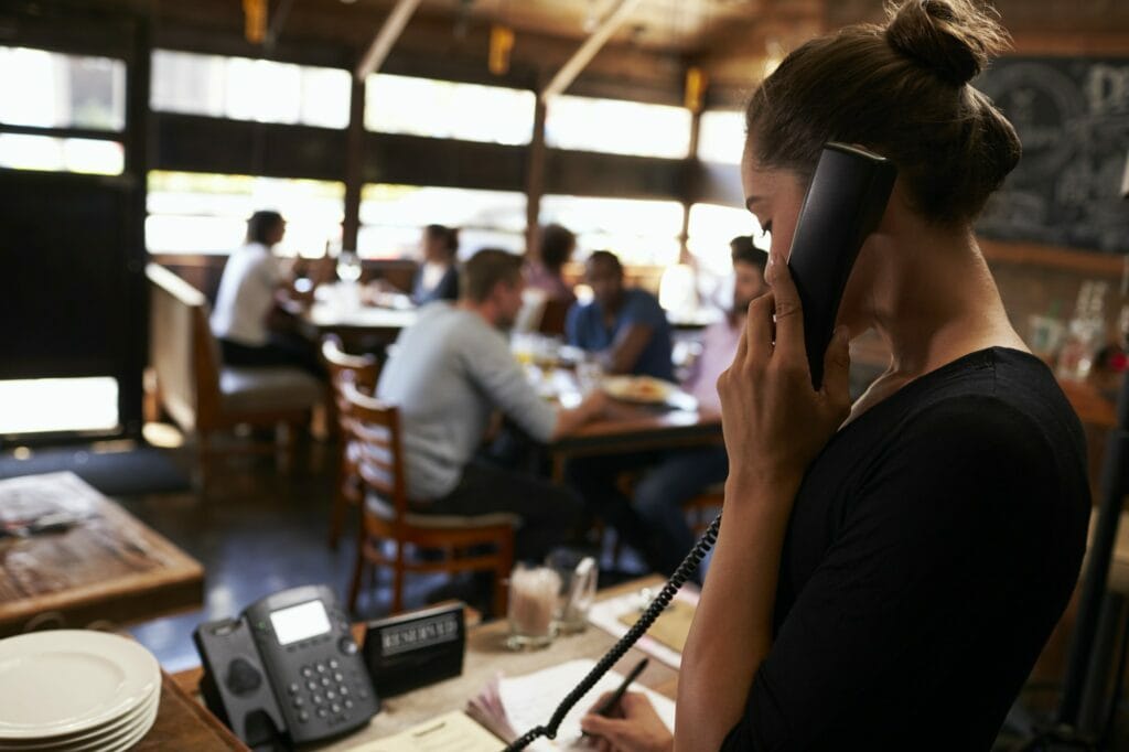 Young woman taking a reservation by phone at a restaurant