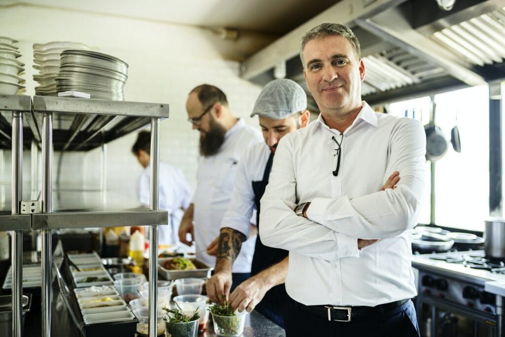 Restaurant kitchen chef with staff and manager